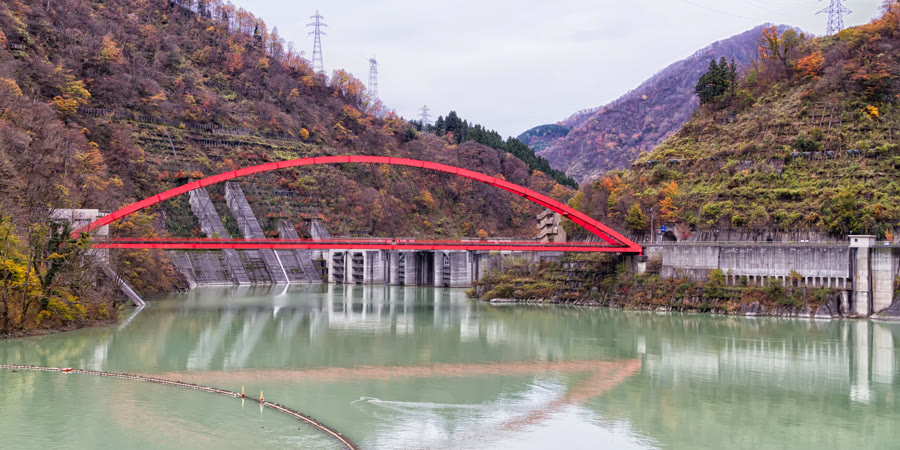 赤い橋がかかる川と山の風景